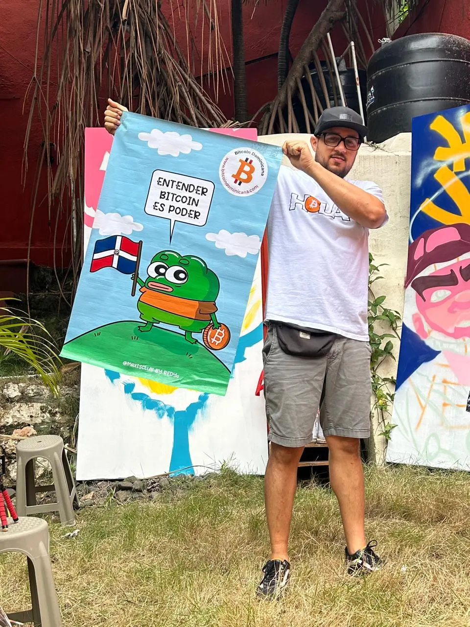 Integrante de Bitcoin Dominicana muestra un cartel con la bandera dominicana y el logo de Bitcoin.
