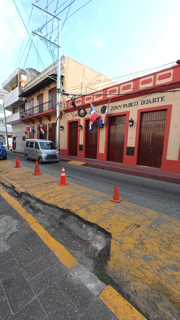 Calle histórica de la Zona Colonial de Santo Domingo, República Dominicana, con edificio colonial y banderas dominicanas