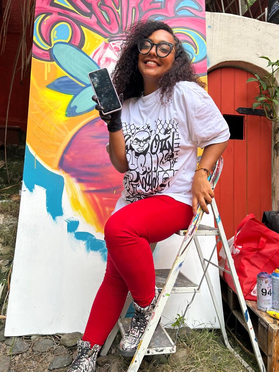Artista mostrando su billetera Bitcoin frente a un mural en la Zona Colonial, Santo Domingo