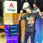 Asistente con la camiseta de Bitcoin Dominicana frente a los cubos de patrocinadores de Dominicana Tech Week 2026.