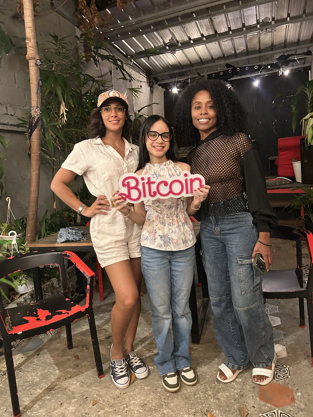 Tres asistentes sostienen un letrero de Bitcoin durante el encuentro en Santo Domingo