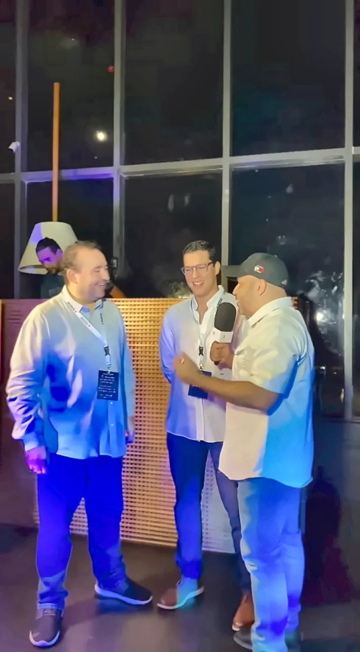 Tres asistentes conversan con un micrófono durante el encuentro de tecnología e innovación en República Dominicana.
