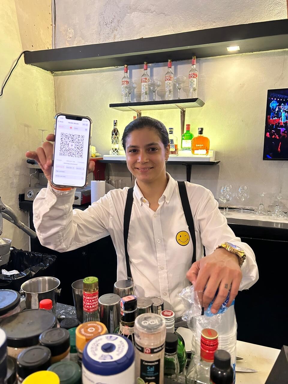 Bartender mostrando un código QR de pago Lightning en un bar de la Zona Colonial, República Dominicana