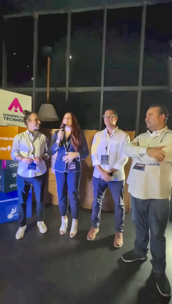 Miembros del equipo organizador de Dominicana Tech Week 2026 se dirigen a los asistentes con micrófono en mano.