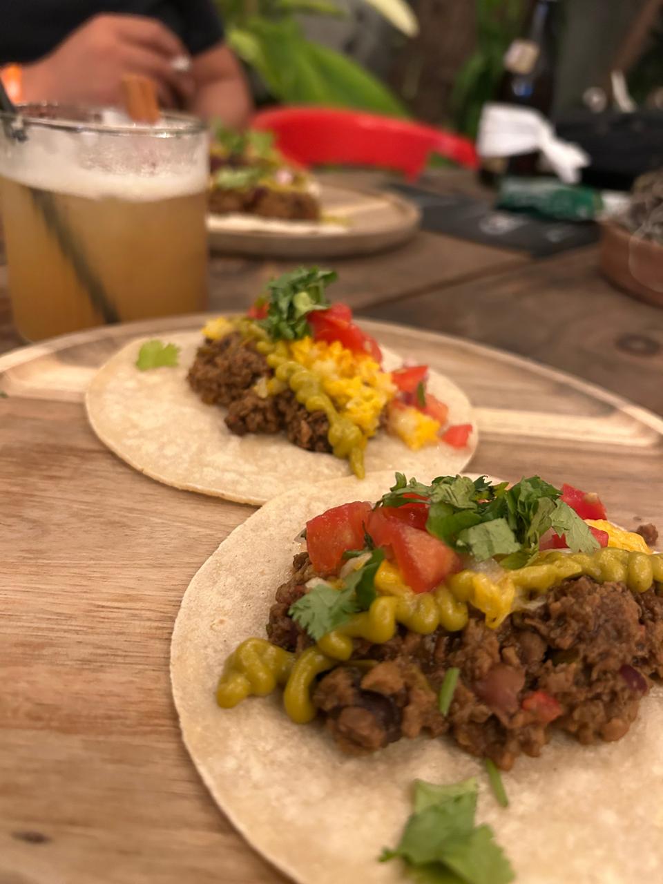Tacos de carne guisada con guacamole, queso y pico de gallo junto a un cóctel con canela en The Perpetual Lab, Zona Colonial