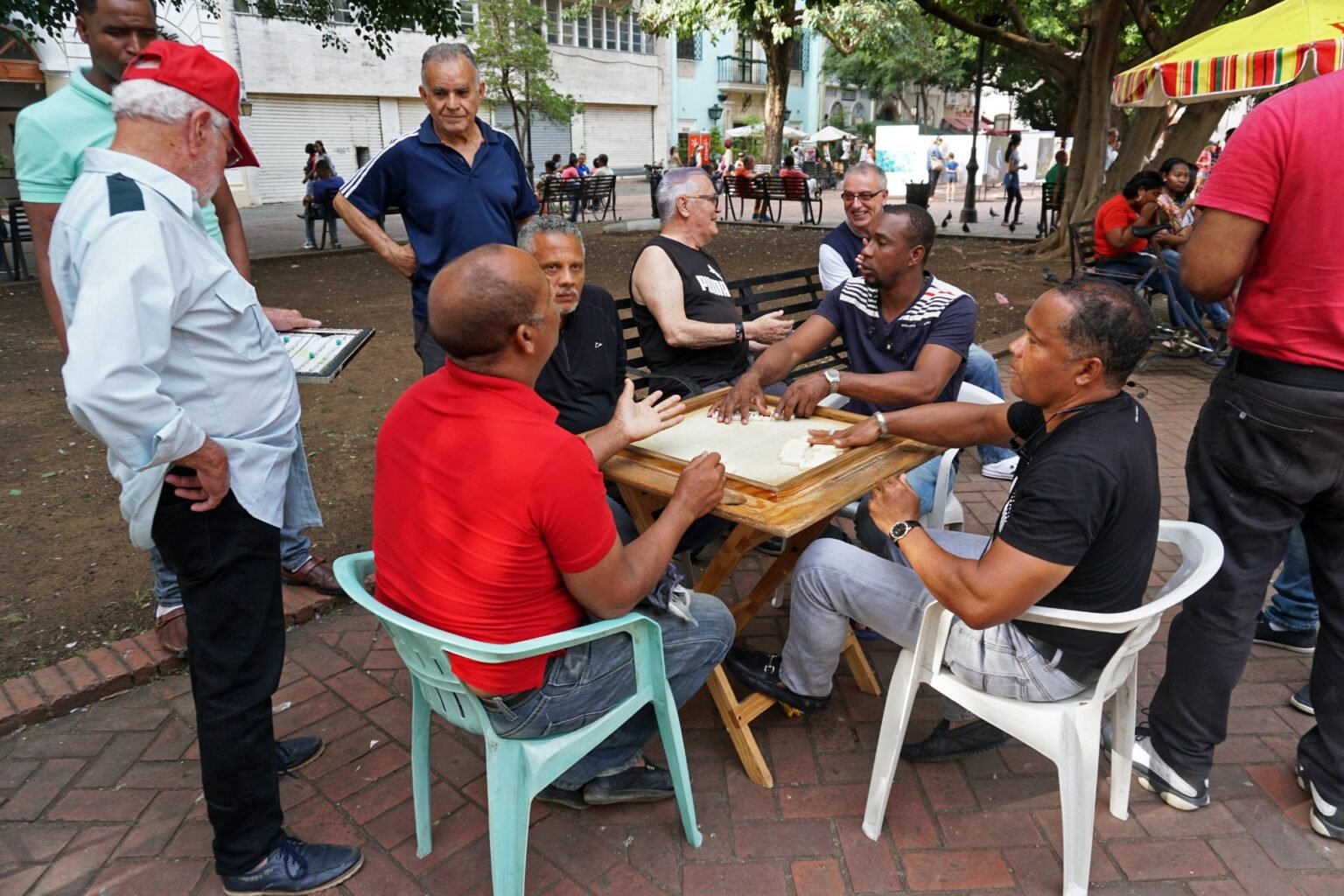 Grupo de personas jugando dominó en una mesa del Parque Colón, Ciudad Colonial de Santo Domingo