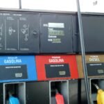 Surtidor de combustible en Santo Domingo con etiquetas de precio por galón en pesos dominicanos para gasolina regular, premium y diésel.