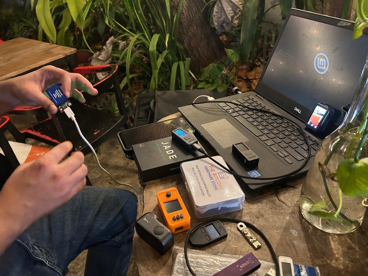 Mesa con varias hardware wallets, entre ellas un SeedSigner naranja, junto a un laptop