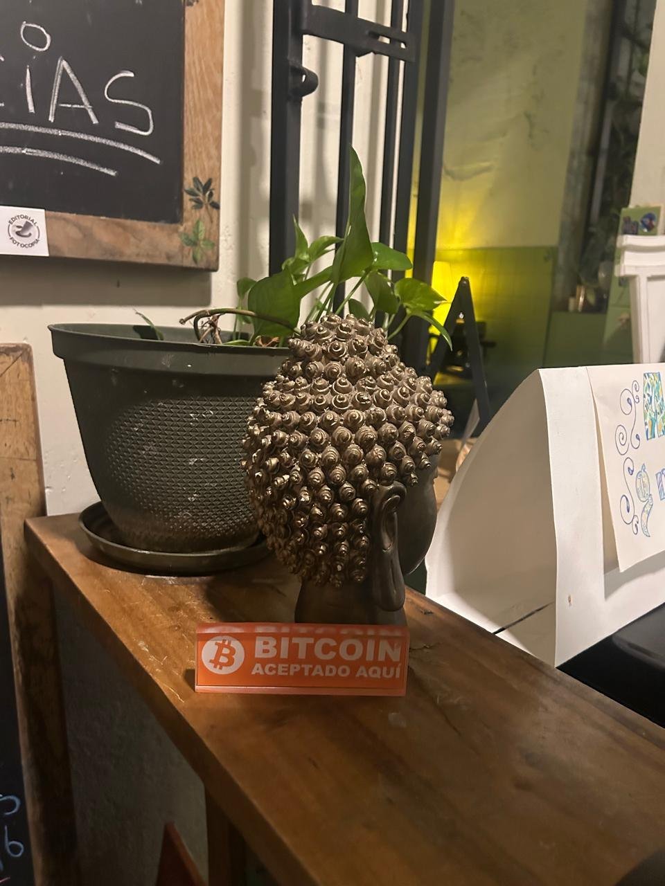 Letrero naranja «Bitcoin aceptado aquí» en el mostrador de The Perpetual Lab