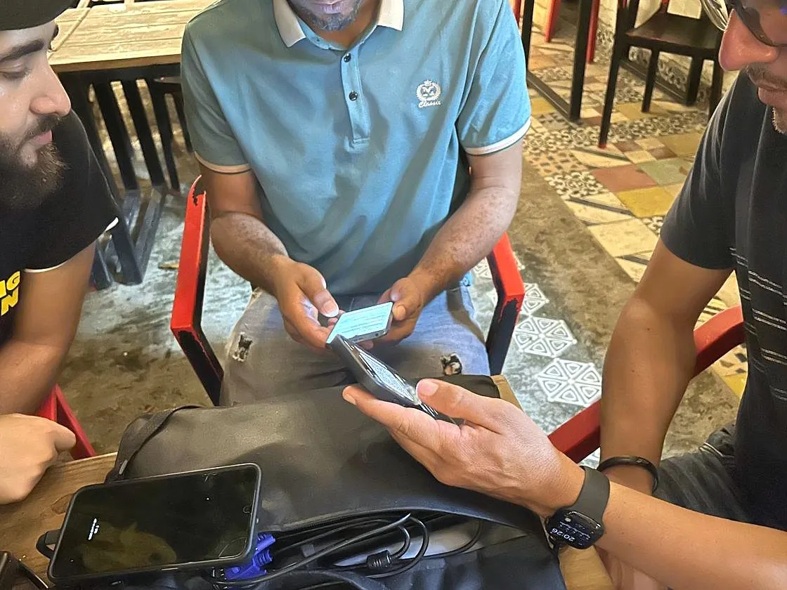 Carlos Gutiérrez, de Quisqueya Project (izquierda), acompaña a dos participantes que revisan wallets de Bitcoin y Lightning en sus teléfonos